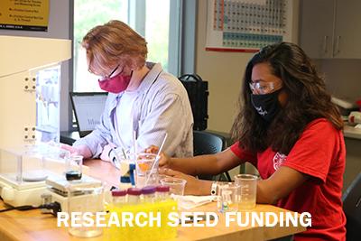 Two student researchers with the text Research Seed Funding