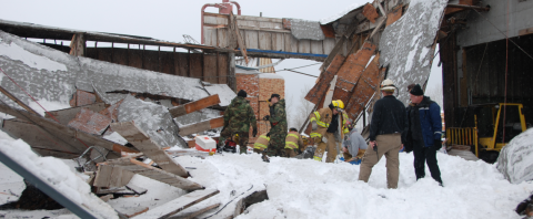 Workers surveying a collapsed roof